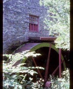 Part of exterior of preserved watermill building showing wheel