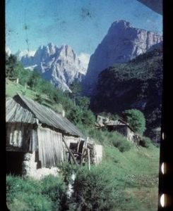 Pair of small derelict watermill buildings with mountains in background