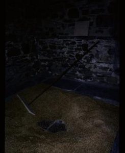 Appears to show grain on floor of kiln, with shovelling instrument