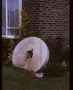 Millstone leaning against wall of private house