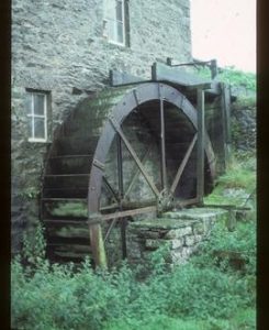 Exterior view of preserved stone watermill building with wheel