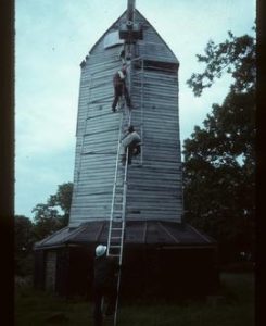 Men working on removal of surviving sail of derelict post mill