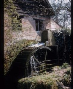 Part of exterior of watermill building with turning wheel