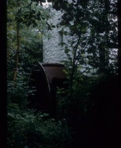 Exterior view of stone watermill building with wheel