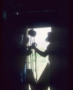 Two men at mill door using winch