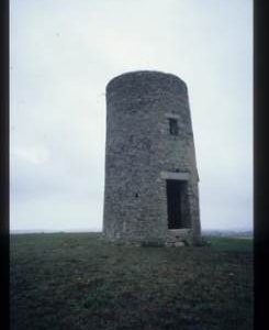 Shell of small, slender stone tower mill (leaning)