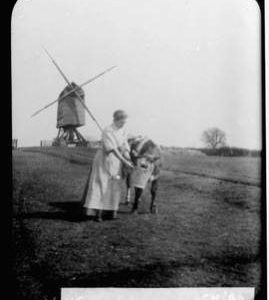 Mill with sweeps but no sails and woman feeding cow