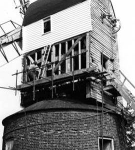 Post mill, Ramsey, with side cladding removed and two millwrights at work